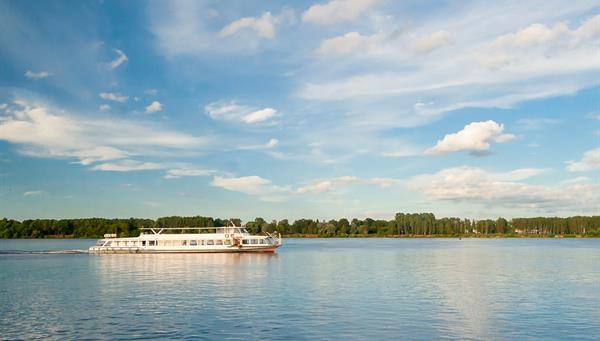 Barco turístico navegando por el río Rhin en un claro día de verano.
